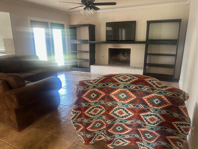 606 NW 14th St, Andrews, TX 79714 - living area featuring a ceiling fan, crown molding, a fireplace, and tile patterned floors