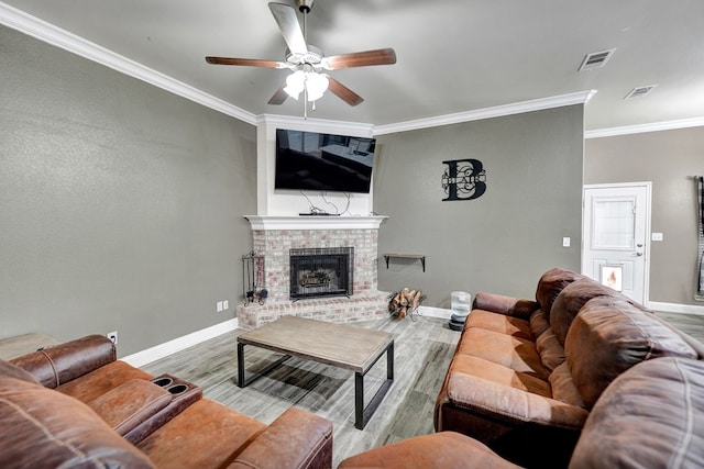 living room featuring crown molding, a fireplace, ceiling fan, and light wood-type flooring