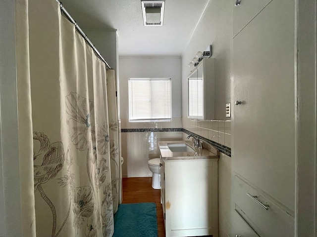 bathroom with vanity, toilet, wood-type flooring, and tile walls