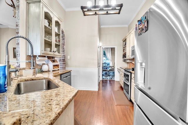 1000 S Nelson Rd, Monahans, TX 79756 - kitchen with stainless steel appliances, ornamental molding, light wood finished floors, a wainscoted wall, and glass insert cabinets
