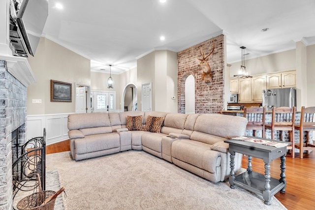 1000 S Nelson Rd, Monahans, TX 79756 - living area with arched walkways, light wood-style flooring, a fireplace, ornamental molding, and recessed lighting