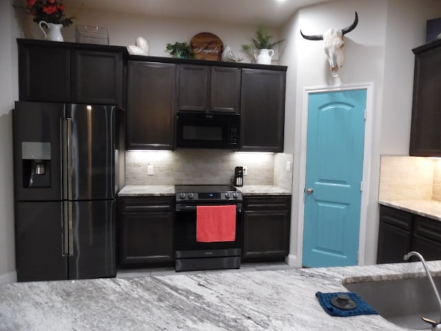 kitchen featuring appliances with stainless steel finishes, tasteful backsplash, light stone counters, and sink