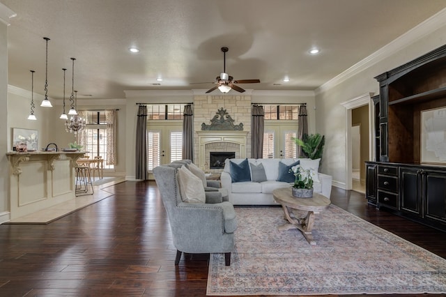 259 County Rd 304, Seminole, TX 79360 - living room featuring crown molding, dark wood-type flooring, a stone fireplace, a ceiling fan, and baseboards