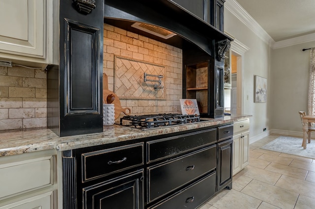 259 County Rd 304, Seminole, TX 79360 - kitchen with crown molding, dark cabinetry, stainless steel gas stovetop, decorative backsplash, and light stone counters