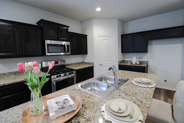 7319 W Pile Ranch Rd, Odessa, TX 79765 - kitchen with appliances with stainless steel finishes, a sink, dark cabinetry, wood finished floors, and recessed lighting