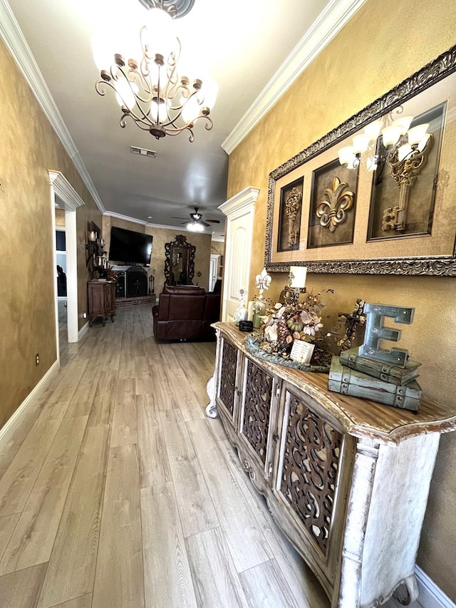 hallway featuring light wood finished floors, a chandelier, crown molding, and baseboards