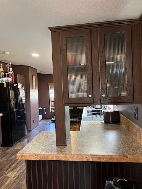 1319 S Broughton Ave, Odessa, TX 79761 - kitchen featuring black refrigerator with ice dispenser, dark brown cabinets, glass insert cabinets, and dark wood-style flooring
