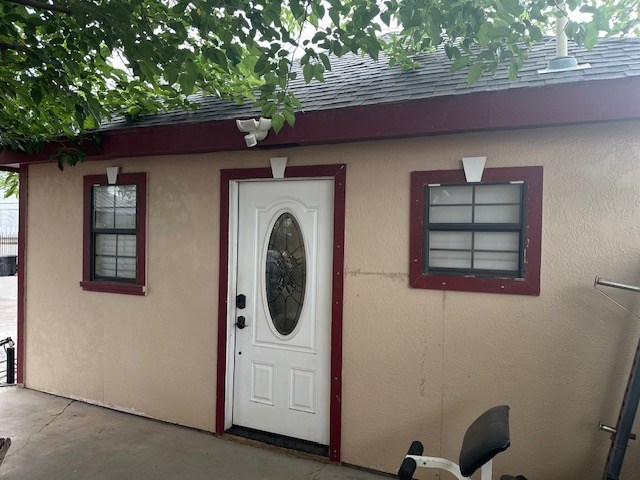 2404 W 10th St, Odessa, TX 79763 - view of exterior entry with roof with shingles and stucco siding