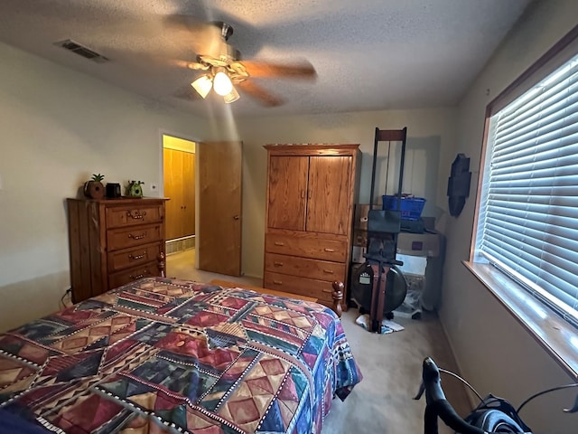 carpeted bedroom featuring ceiling fan and a textured ceiling