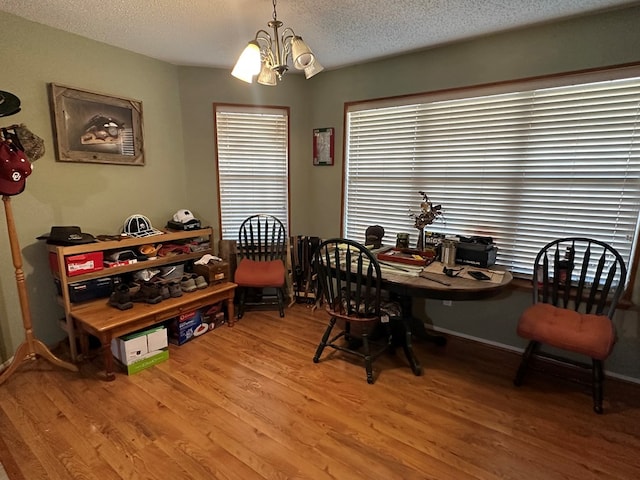 dining room with hardwood / wood-style floors, a textured ceiling, and a notable chandelier