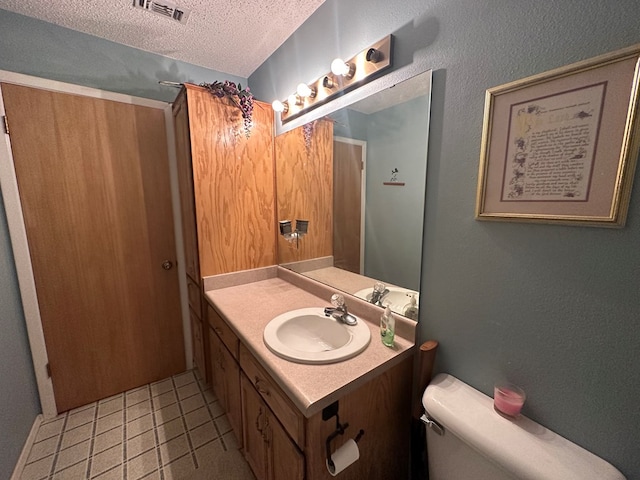 bathroom with tile patterned flooring, vanity, a textured ceiling, and toilet