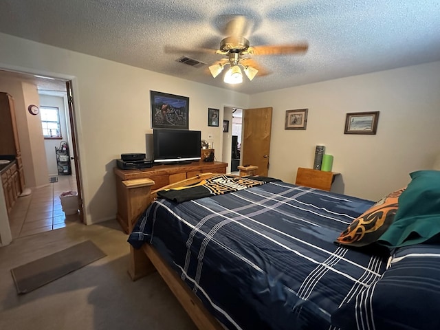 bedroom featuring tile patterned flooring, ceiling fan, and a textured ceiling