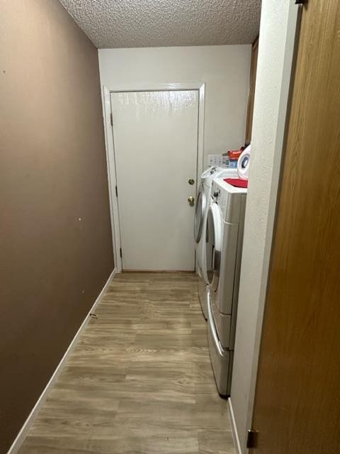 laundry room with a textured ceiling, light hardwood / wood-style flooring, and washer and clothes dryer