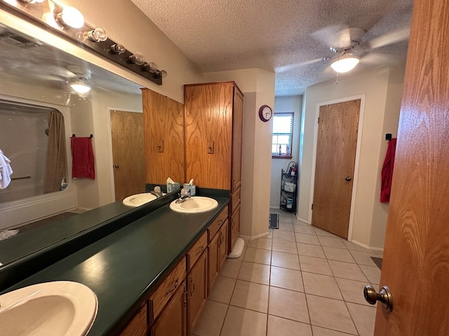 bathroom with tile patterned flooring, vanity, ceiling fan, and a textured ceiling