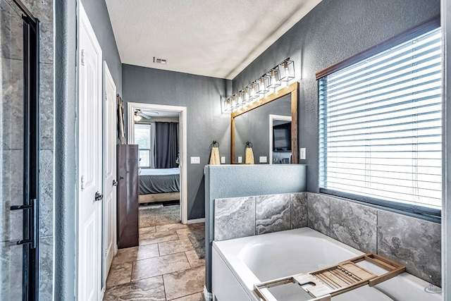 6411 Hall Of Fame, Midland, TX 79706 - bathroom with ensuite bathroom, a textured wall, a garden tub, and a textured ceiling