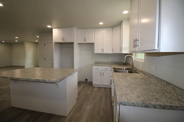 607 NW 11th St, Andrews, TX 79714 - kitchen with dark wood-style floors, white cabinetry, a kitchen island, recessed lighting, and a breakfast bar area