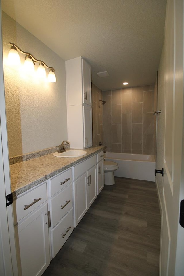 607 NW 11th St, Andrews, TX 79714 - bathroom featuring vanity, wood finished floors, a textured ceiling, recessed lighting, and  shower combination