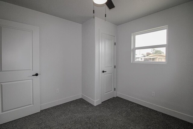 607 NW 11th St, Andrews, TX 79714 - unfurnished bedroom with dark carpet and a ceiling fan
