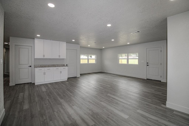 607 NW 11th St, Andrews, TX 79714 - unfurnished living room with a textured ceiling, dark wood-type flooring, and recessed lighting