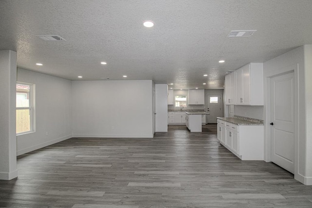 607 NW 11th St, Andrews, TX 79714 - kitchen with open floor plan, a textured ceiling, recessed lighting, white cabinetry, and wood finished floors