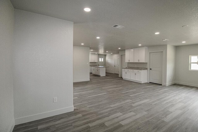 607 NW 11th St, Andrews, TX 79714 - unfurnished living room featuring recessed lighting, wood finished floors, and a textured ceiling