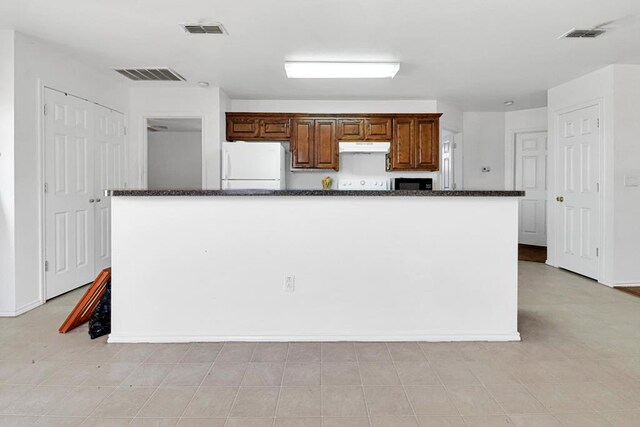 1206 Alameda Ave, Odessa, TX 79763 - kitchen featuring freestanding refrigerator, under cabinet range hood, dark stone counters, baseboards, and a kitchen island
