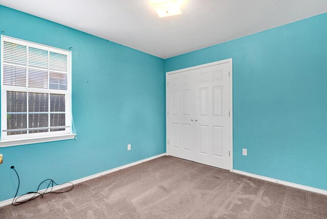 1206 Alameda Ave, Odessa, TX 79763 - unfurnished bedroom with carpet, baseboards, and a closet