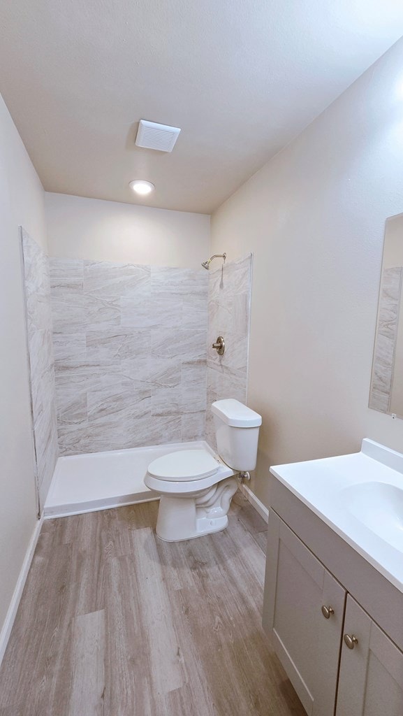 bathroom featuring a shower stall, vanity, toilet, and wood finished floors