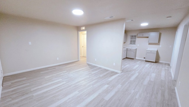 interior space with light wood-type flooring, visible vents, and baseboards