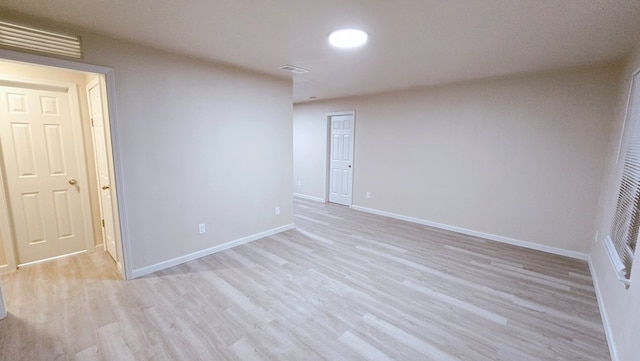 empty room featuring light wood finished floors, baseboards, and visible vents