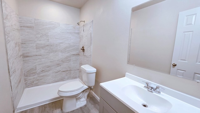 bathroom featuring tiled shower, vanity, toilet, and wood finished floors