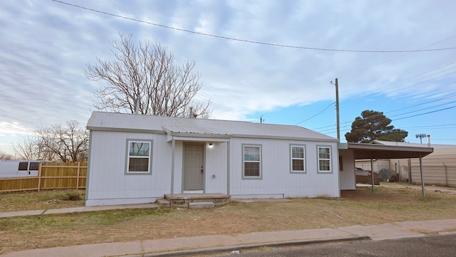 view of front of property featuring an attached carport, metal roof, and fence