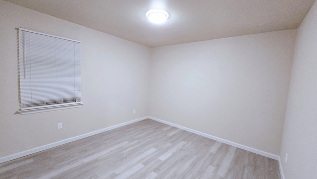 unfurnished room with light wood-style flooring and baseboards