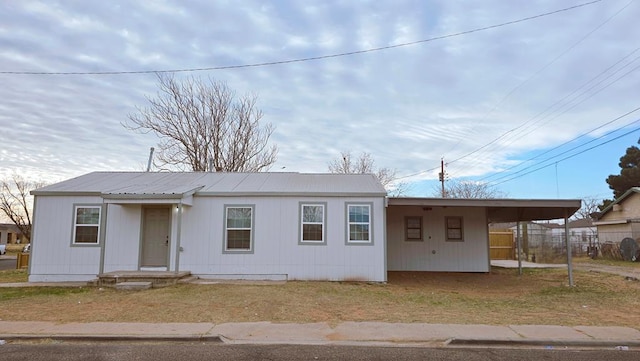 view of front facade featuring driveway, metal roof, and an attached carport