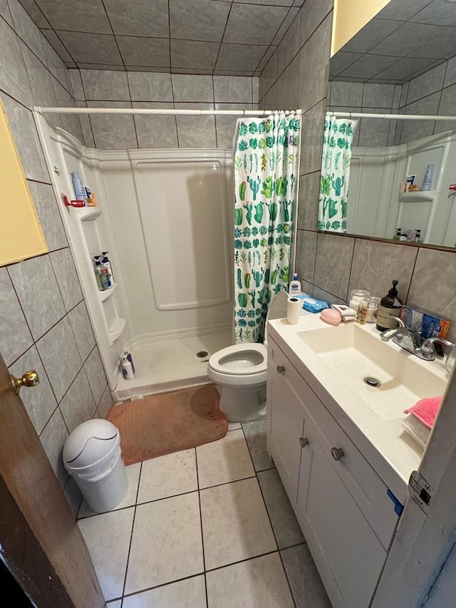 1044 Washington St, Kermit, TX 79745 - full bathroom featuring tile walls, toilet, vanity, a stall shower, and tile patterned flooring