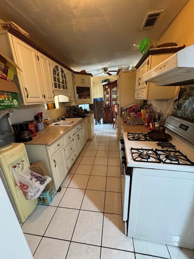 1044 Washington St, Kermit, TX 79745 - kitchen featuring gas range gas stove, under cabinet range hood, a ceiling fan, light tile patterned floors, and a sink