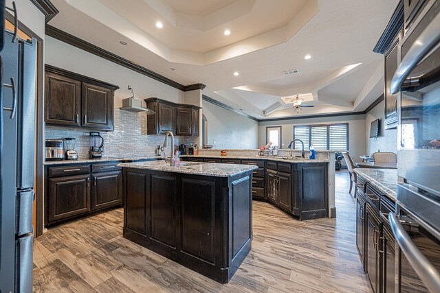 14105 County Rd 122, Odessa, TX 79765 - kitchen featuring a raised ceiling, an island with sink, recessed lighting, a sink, and tasteful backsplash