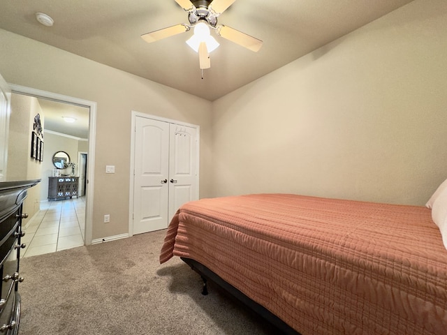 bedroom with light tile patterned flooring, ceiling fan, light carpet, and baseboards