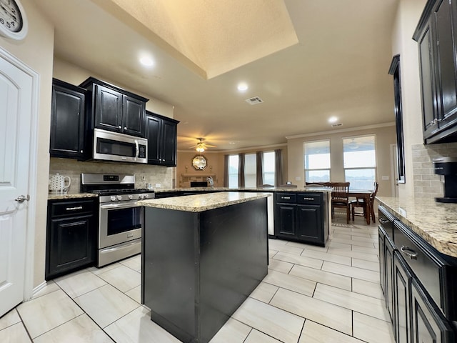 kitchen featuring a kitchen island, backsplash, dark cabinets, stainless steel appliances, and recessed lighting