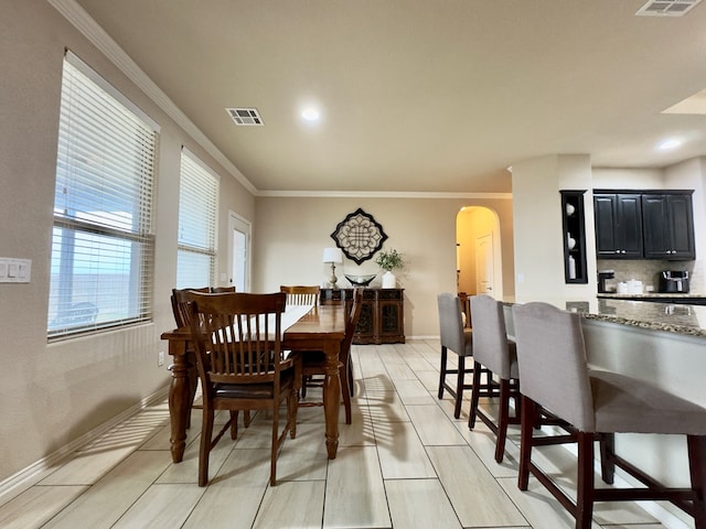 dining area featuring crown molding, arched walkways, baseboards, and visible vents