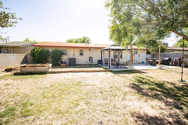 rear view of property featuring fence, a gazebo, central AC, a patio area, and a yard