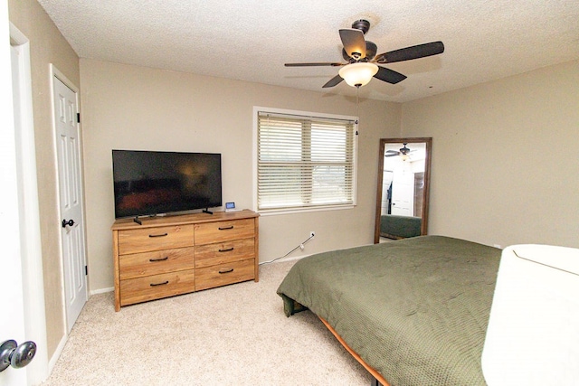 bedroom with a textured ceiling, light colored carpet, and ceiling fan