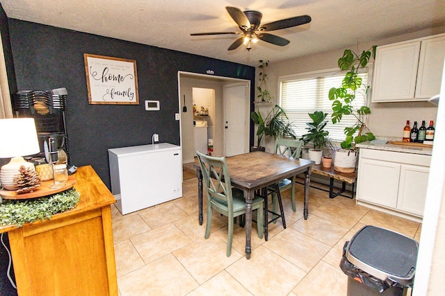 dining area featuring a ceiling fan, a textured ceiling, and light tile patterned floors