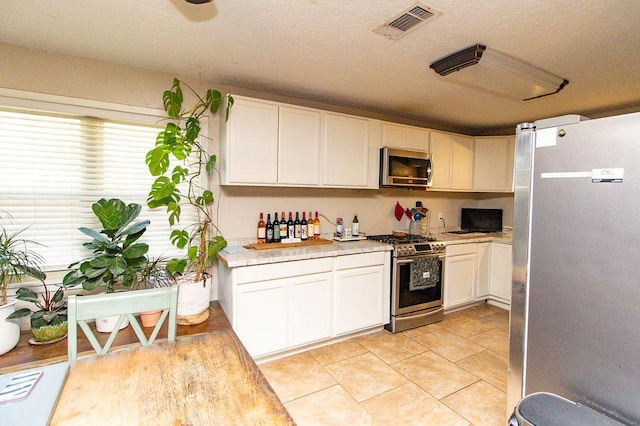 kitchen featuring a textured ceiling, visible vents, appliances with stainless steel finishes, light countertops, and white cabinetry