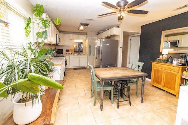 dining space with visible vents, ceiling fan, and light tile patterned floors