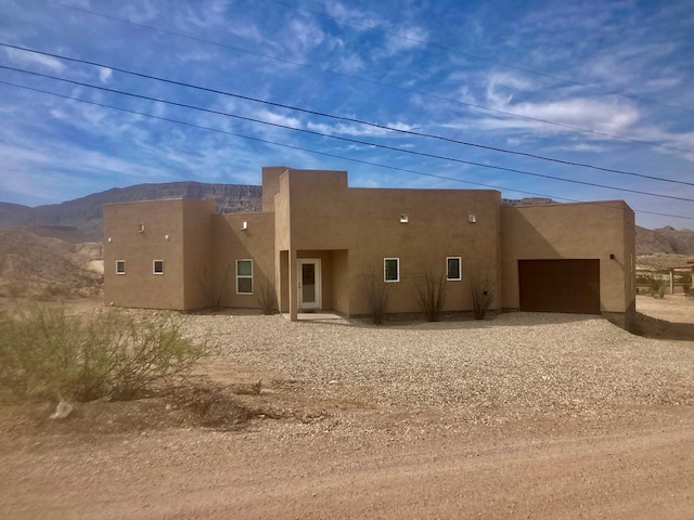 420 Santana Dr, Lajitas, TX 79852 - rear view of house featuring dirt driveway, a mountain view, stucco siding, and an attached garage