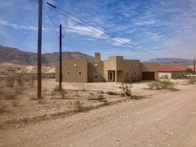 420 Santana Dr, Lajitas, TX 79852 - view of front of property with stucco siding, a mountain view, and an attached garage