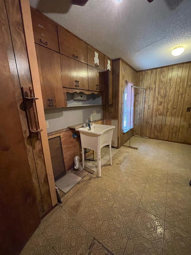 kitchen featuring a textured ceiling and wooden walls