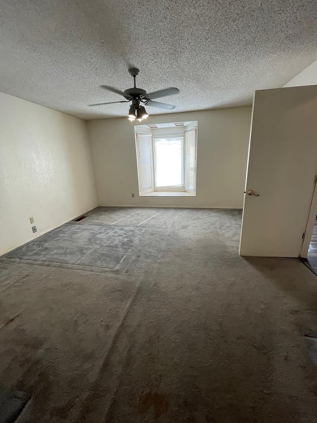 carpeted spare room featuring a textured ceiling and ceiling fan