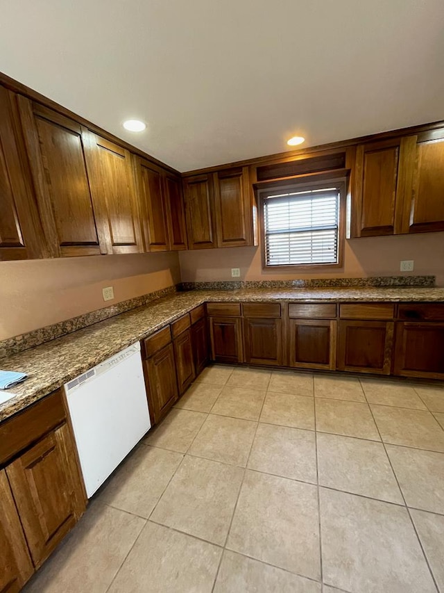 kitchen with white dishwasher, light tile patterned flooring, and light stone countertops